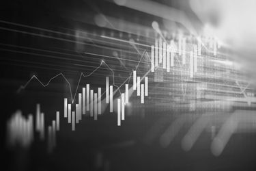 A black and white image of a financial chart with candlestick patterns and line graphs on a digital screen.